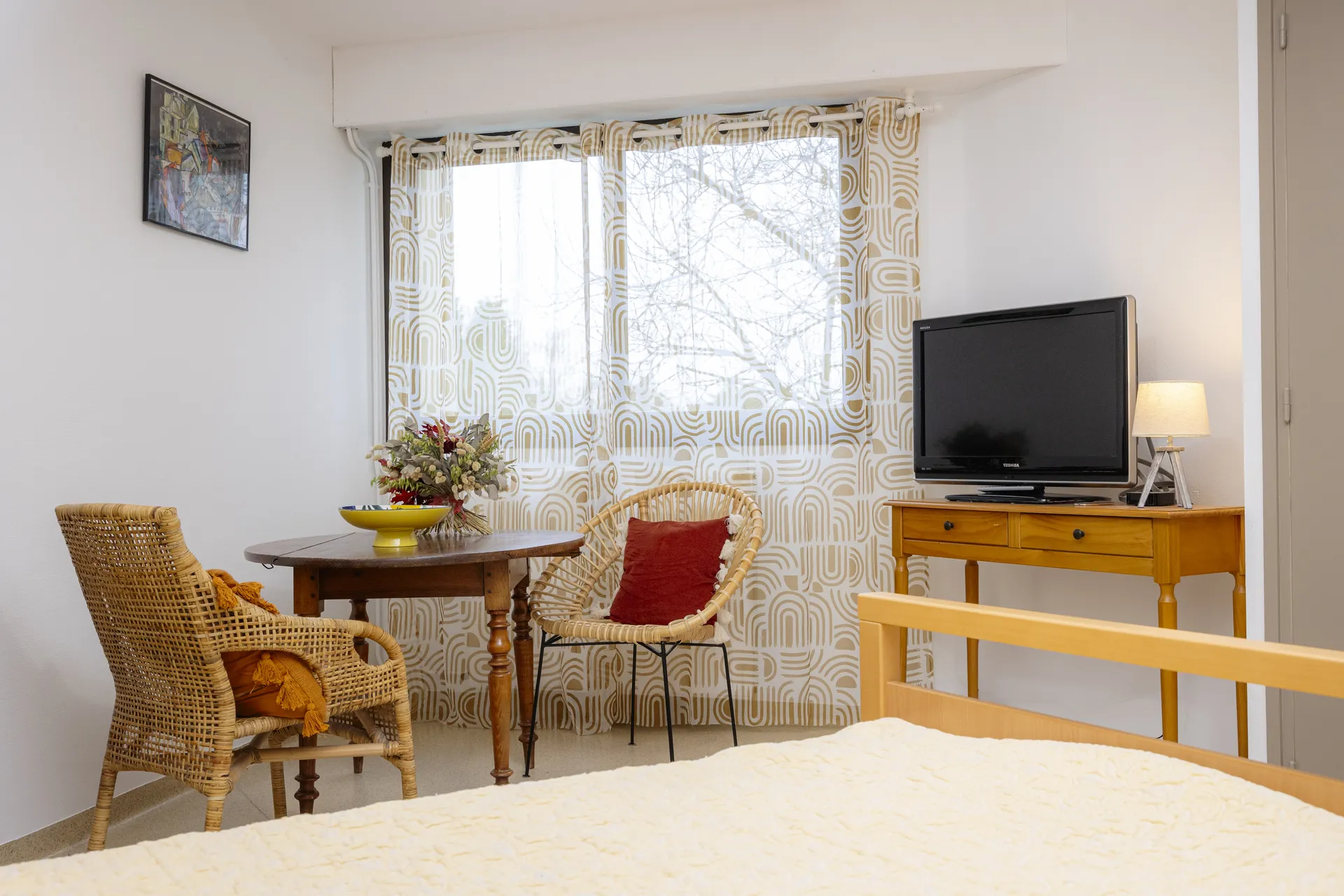 Coin salon de chambre avec mobilier en bois, télévision et vue sur jardin dans l'EHPAD Le Clos du Moulin Divatte-sur-Loire