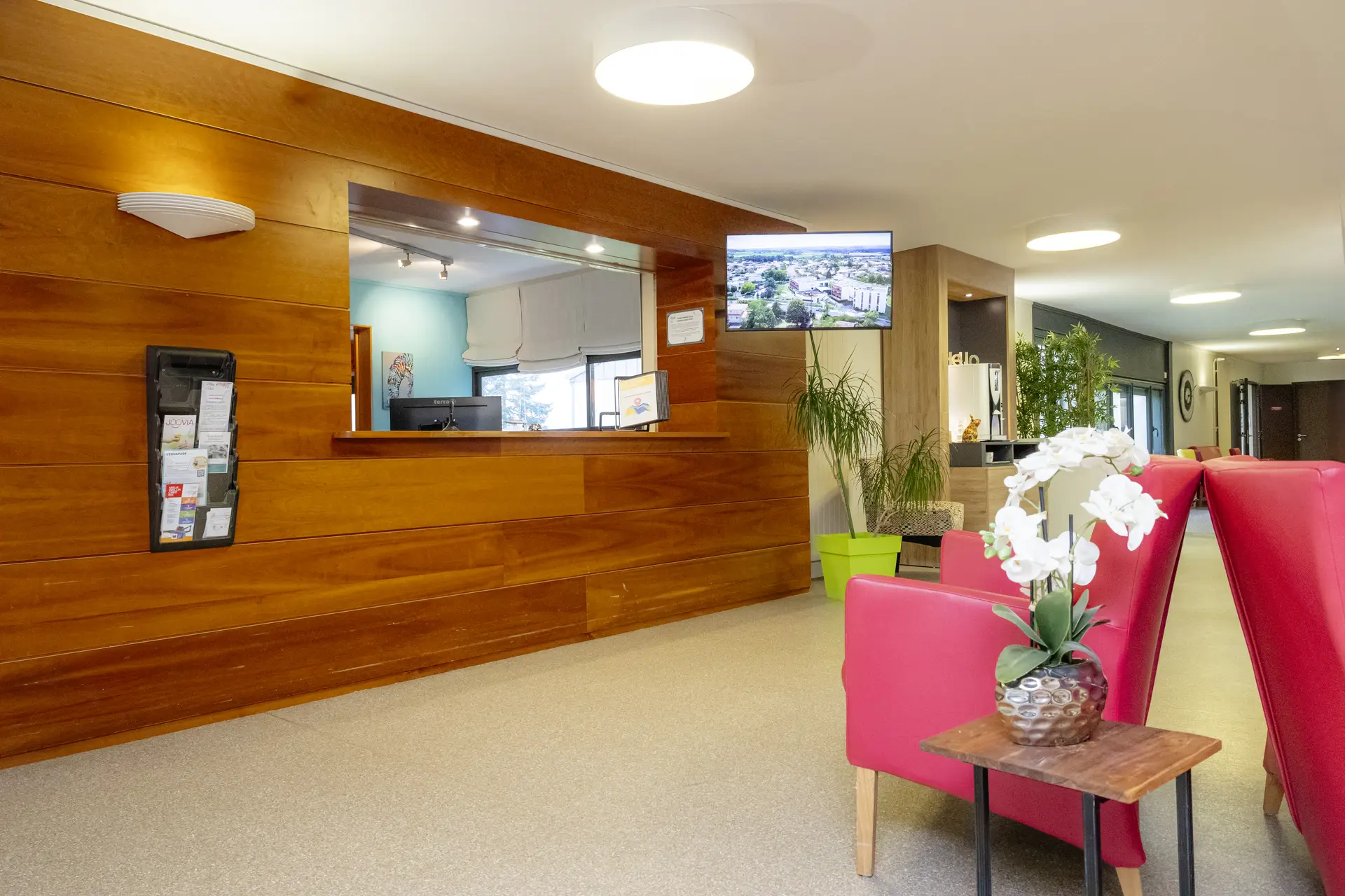 Hall d'accueil moderne avec réception en bois et banquettes roses de l'EHPAD Le Clos du Moulin Divatte-sur-Loire
