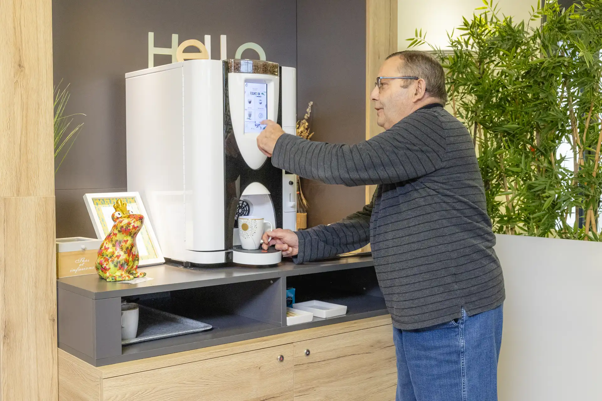 Visiteur utilisant la machine à café automatique dans l'espace accueil moderne de l'EHPAD Le Clos du Moulin Divatte-sur-Loire